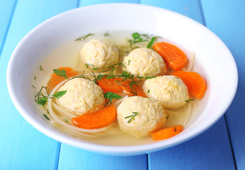 Soup with meatballs and noodles in bowl on wooden background