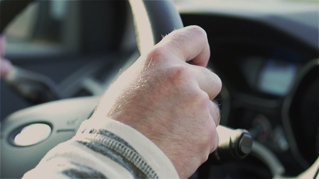 Man hands holding wheel and driving a car