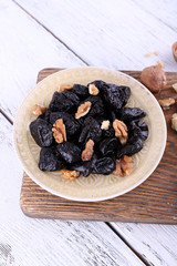 Wooden board with plate of prunes and walnuts