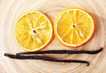 Dried slices of orange with vanilla beans on wooden background