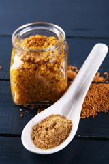 Mustard in glass jar and mustard powder in spoon
