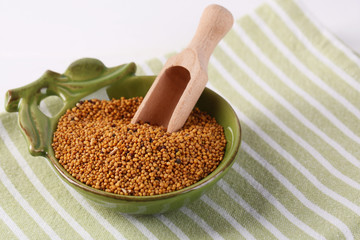 Mustard seeds in bowl on  wooden background