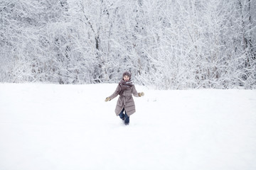 Happy little girl running on the background of snow covered wint