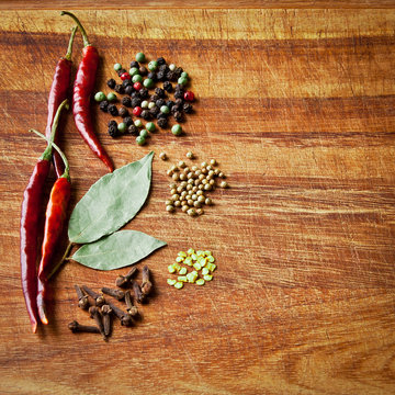 Dried red chili peppers and spices on rustic, dark wood cutting