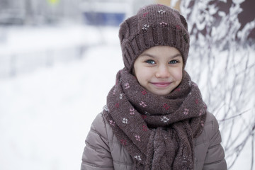 Happy little girl on the background of a winter park