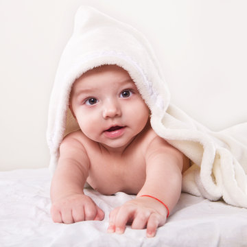 the infant lying on white towel