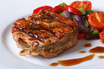 Delicious pork steak with vegetables and sauce close-up