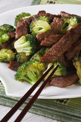 pieces of beef with broccoli close-up and chopsticks. Vertical