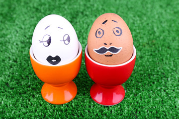 Pair of eggs in egg cups on green background