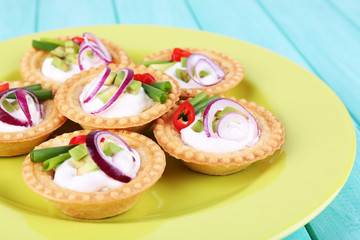 Tartlets with greens and vegetables with sauce on plate on