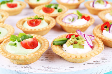 Tartlets with greens and vegetables with sauce on tray close-up
