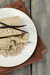 Sunflower halva on plate, on wooden background