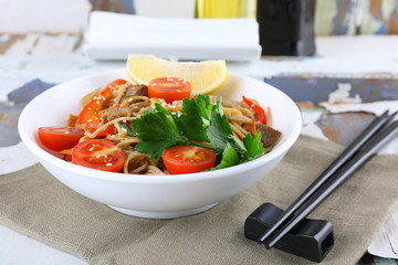 Chinese noodles with vegetables and roasted meat in bowl