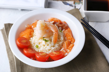 Boiled rice and shrimps, salmon and tomatoes in bowl,