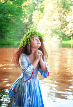 Beautiful woman with long medieval dress praying in the water