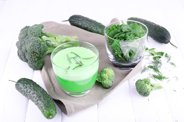 Glass of green smoothie and herbs with vegetables