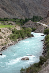 green water of the mountain river flowing through a valley among