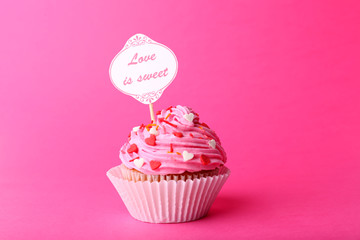 Delicious cupcake with inscription on pink background