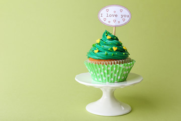 Delicious cupcake with inscription on green background