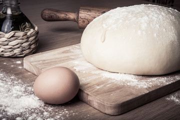dough on a board with flour. olive oil, eggs, rolling pin