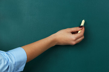 Naklejka premium Female hand writes on blackboard close-up