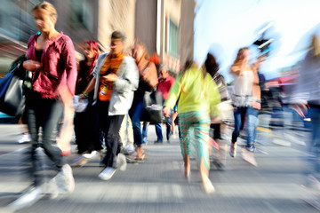 Zoom and motion blurred crowd crossing street