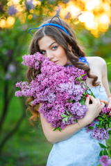 Fototapeta premium beautiful woman with a bouquet of lilacs in the spring