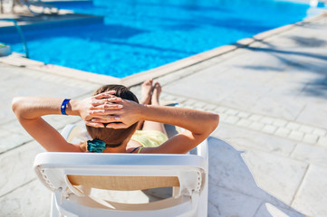 woman chaise longue on the background of the pool at the hotel