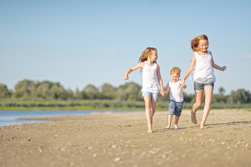 three children playing on beach in summer