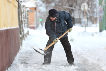 Caucasian woman cleaning snow from sidewalk with shovel