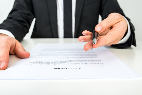Businessman offering you to sign a document with focus to the te