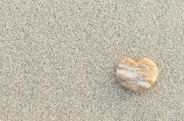 Fototapeta na wymiar Heart shaped pebble on the sand beach