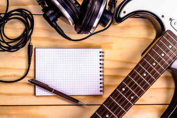 open notebook with electric guitar on wooden background