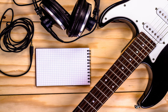 open notebook with electric guitar on wooden background