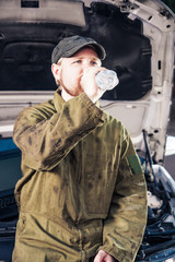 Man Sitting on Engine Drinking Water