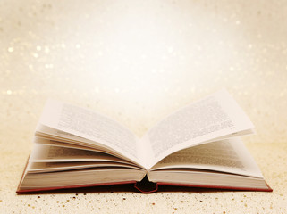 Open book on the sparkly vintage golden background