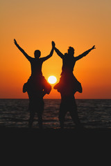 silhouette teens sitting on shoulders of friends in sunset