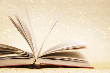 Open book on the sparkly vintage golden background