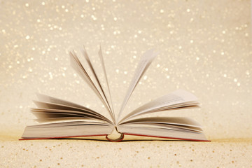 Open book on the sparkly vintage golden background