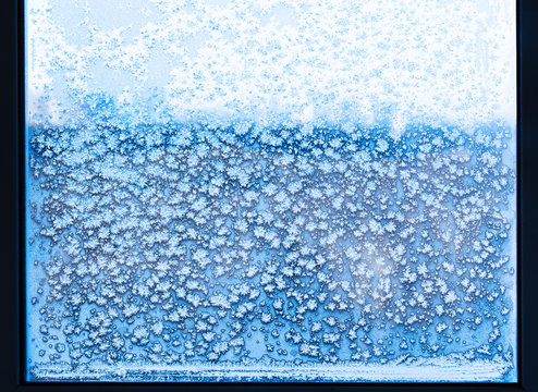 snowflakes and frost pattern on frozen window © vvoe