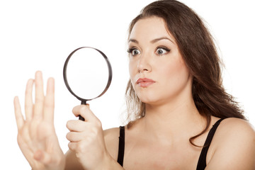 astonished woman looking at her nails with a magnifying glass