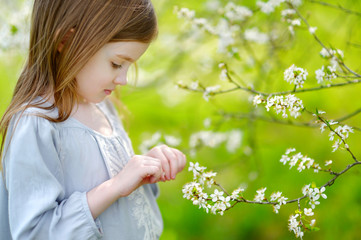 Adorable little girl in blooming cherry garden