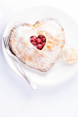Heart shaped cherry pie with vanilla ice cream on white