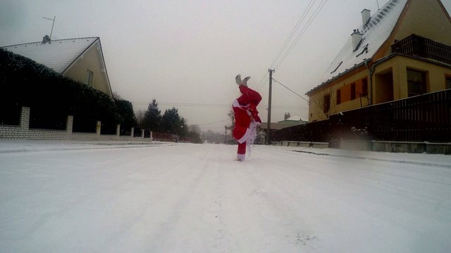 Santa Claus dancing break dance in the snow on the street