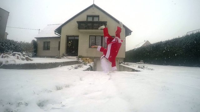 Santa Claus dancing break dance in the snow on the street