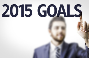 Business man pointing to transparent board with text: 2015 Goals