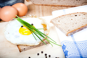 Spiegelei auf Brotscheibe mit Petersilie auf Holzbrett