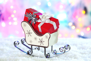 Wooden toy sledge with Christmas gifts  on shiny background