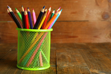 Colorful pencils in metal holder on rustic wooden background