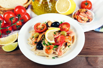 Tasty pasta with shrimps, mussels, black olives and tomato